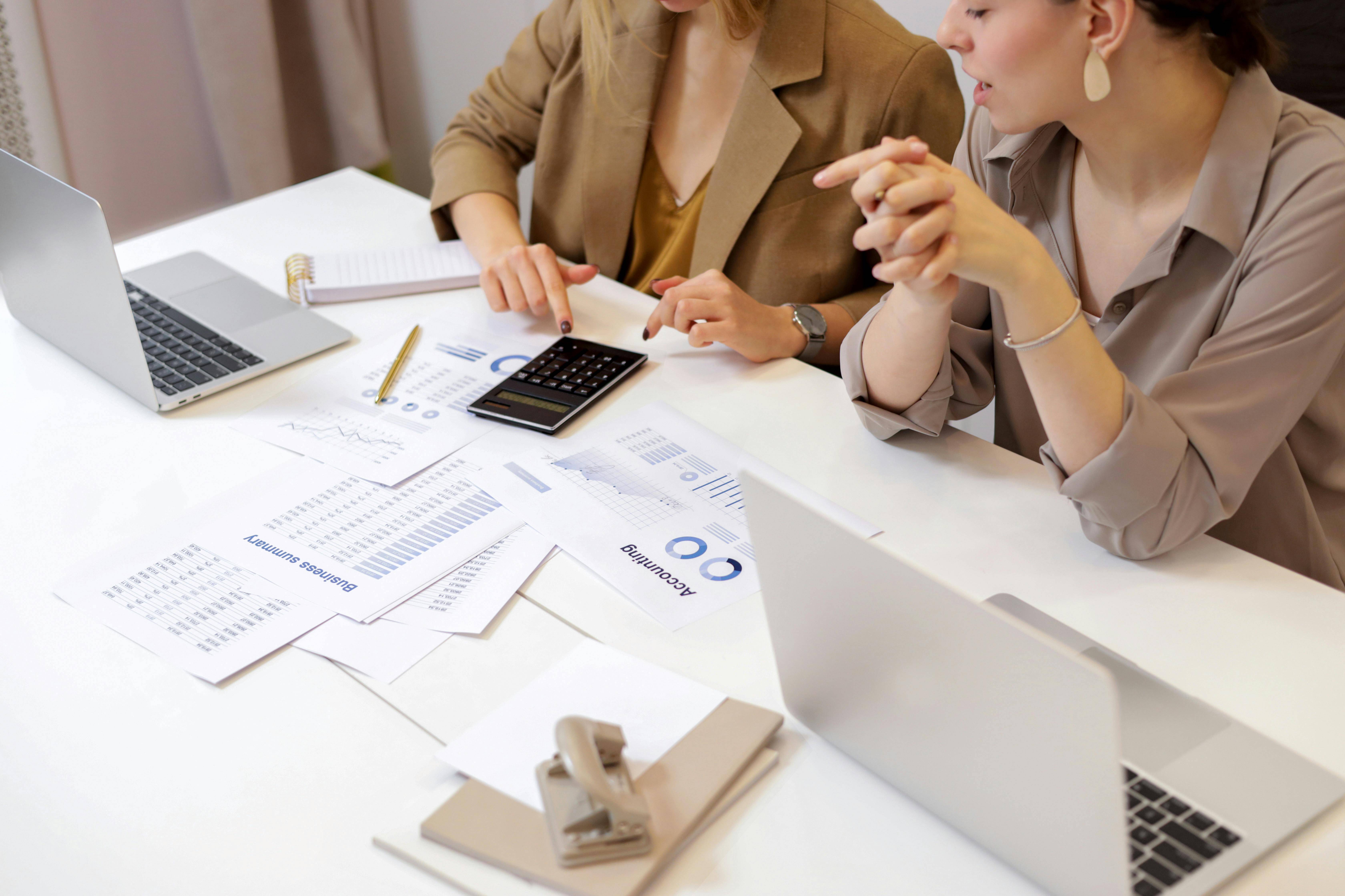 two people working at desk covered in financial paperwork