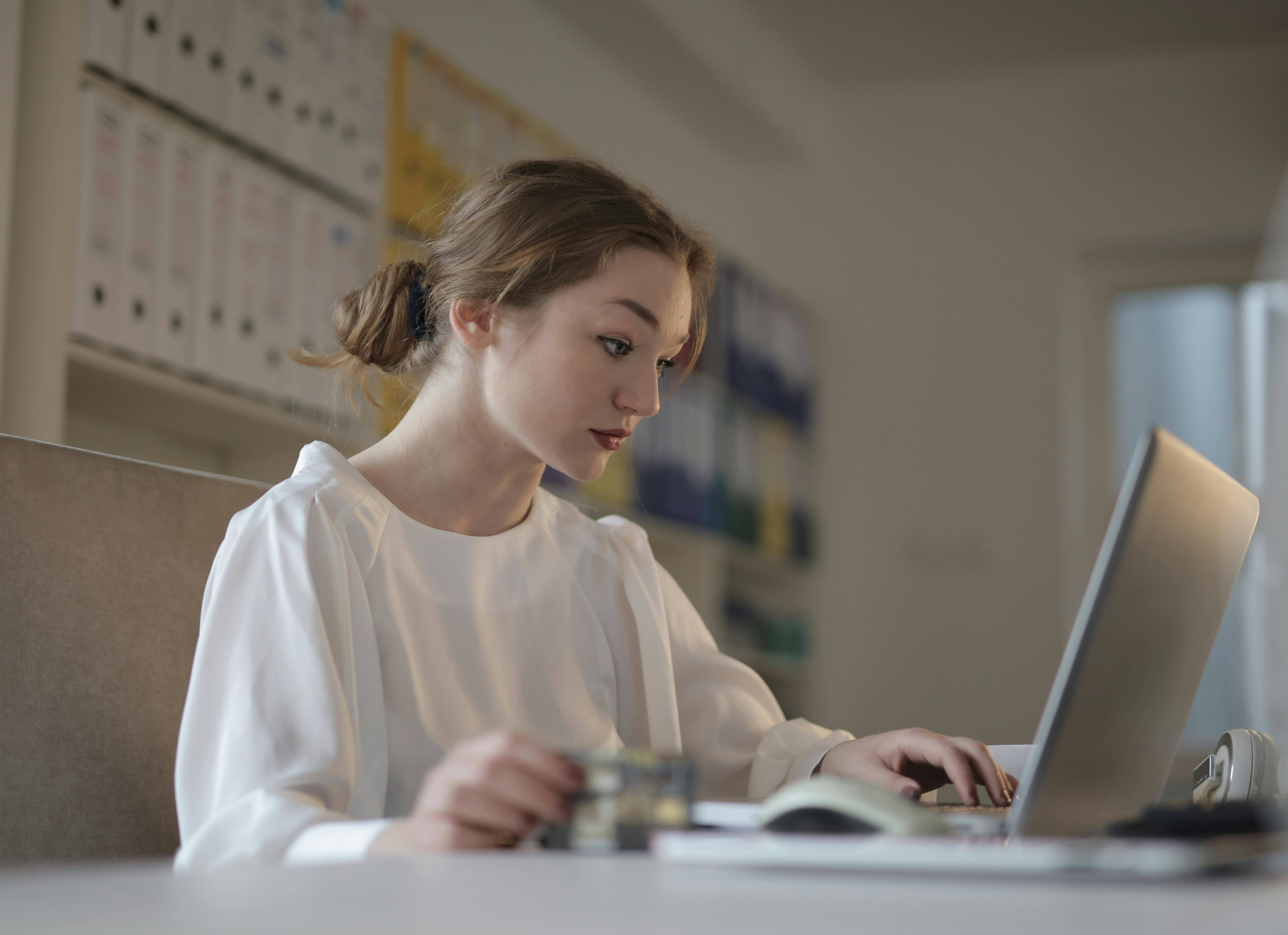 woman sits at desk, concentrating on her computer